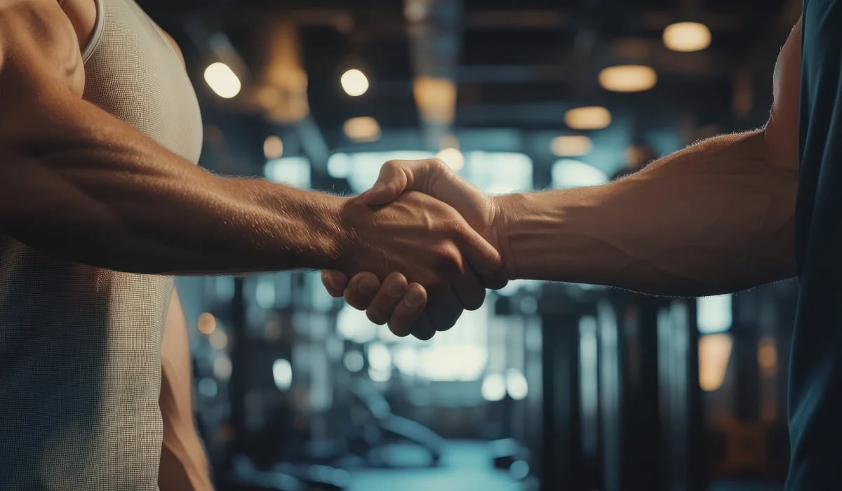 Two people shaking hands in a modern office building with blurred interior background and warm lighting